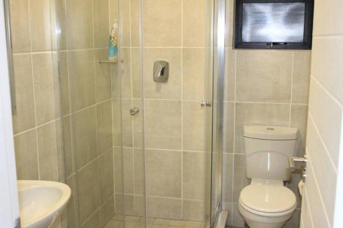 a bathroom with a shower with a toilet and a sink at Greencreek Beautifully furnished apartment in Pretoria