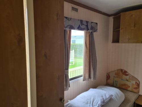 a small bedroom with a window and a bed at 4 Berth Golden Sands Ingoldmells (Siesta) in Ingoldmells