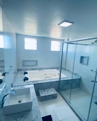 a bathroom with a tub and a shower and a sink at Hotel Real in Cabo Frio