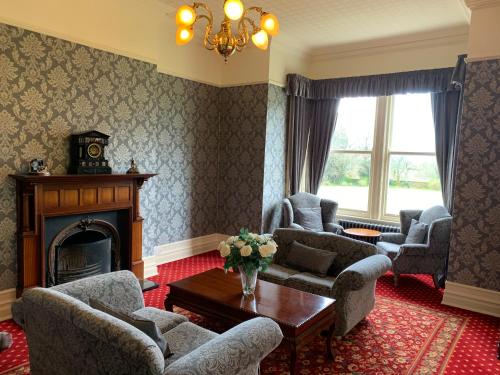 a living room with a fireplace and chairs and a table at Thornton Lodge in Aysgarth