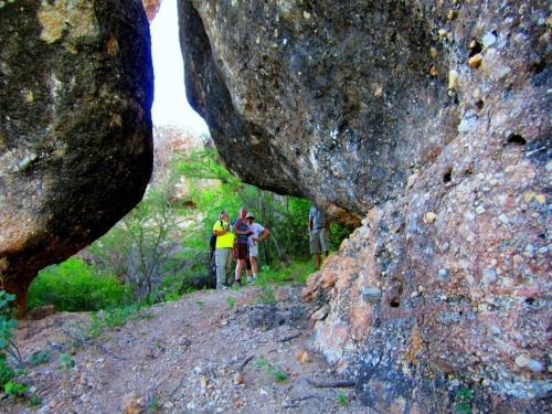 a group of people walking on a trail between large rocks at Sasa Safari Camp & Tours in Outjo
