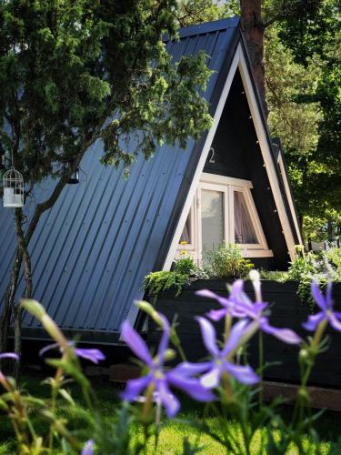a black house with purple flowers in front of it at Camping Milk in Usmenieki
