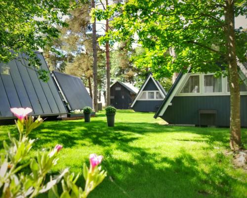 a group of houses in a yard with flowers at Camping Milk in Usmenieki