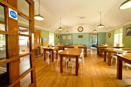 YHA Malham في مالهام: غرفة طعام بطاولات خشبية وساعة على الحائط