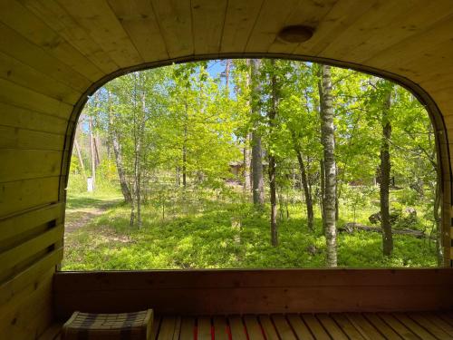 a window in a cabin with a view of a forest at Camping Milk in Usmenieki