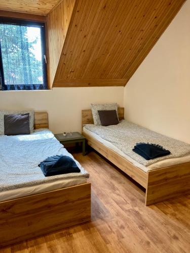 two beds in a room with wooden ceilings at Zöldike Vendégház in Tiszafüred