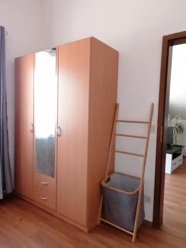 a wooden cabinet with a ladder next to a mirror at Ferienwohnung Magnolie in Langenargen in Langenargen
