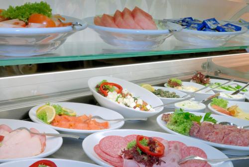 ein Buffet voller Schüsseln mit verschiedenen Speisen in der Unterkunft Hotel Grunewald in Berlin