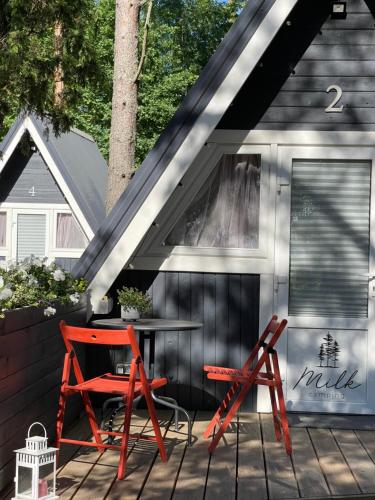 a shed with a table and two chairs on a deck at Camping Milk in Usmenieki