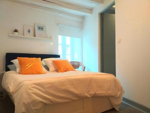 a bedroom with a large bed with orange pillows at A la Grosse Armée - Dans hôtel particulier, hypercentre avec garage, au calme in Bourges