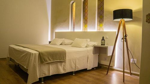 a bedroom with a bed and a lamp at Dom Ravello in Telêmaco Borba