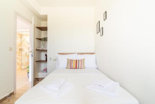 a white bedroom with a white bed with two white towels at Cozy House with Pool near Beach in Gázion