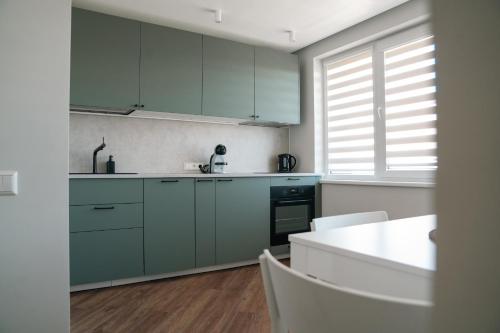 cocina con armarios verdes y encimera blanca en Grey Green Studio Apartment, en Birštonas