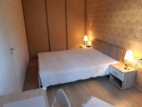 a small bedroom with a white bed and two lamps at Apartment Südalinnas in Haapsalu