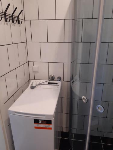 a small white tiled bathroom with a small refrigerator at Apartment Südalinnas in Haapsalu
