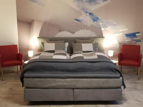 - une chambre avec un grand lit et 2 chaises rouges dans l'établissement Garden-Loft, à Stadelhofen