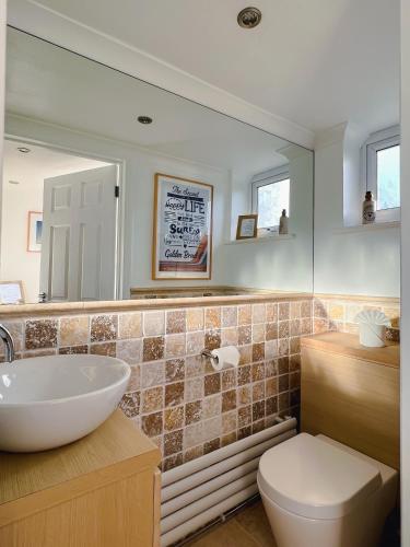 a bathroom with a sink and a toilet and a mirror at Bright & Cosy - Jacuzzi - Log Burner - King Beds in Tangmere