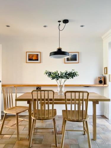 a dining room table with chairs and a vase of flowers at Bright & Cosy - Jacuzzi - Log Burner - King Beds in Tangmere
