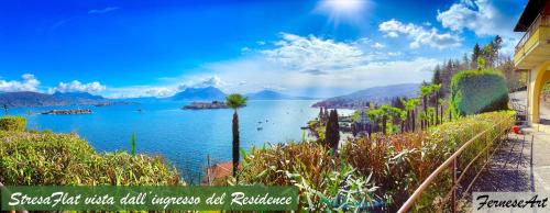 een uitzicht op een meer met palmbomen en een gebouw bij Appartamento vista Lago, giardino spiaggia a Stresa vista Isole Borromee e Golfo Borromeo - STRESAFLAT in Stresa