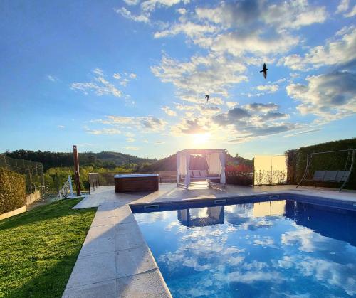 a swimming pool with the sun in the sky at Villa Moura - Pool & Jacuzzi in Póvoa de Lanhoso