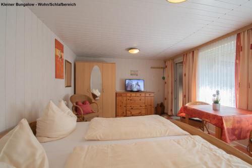 a bedroom with two beds and a table and a television at Kleiner Bungalow - Zum Strand 50m in Ueckeritz