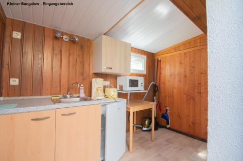 a small kitchen with wooden cabinets and a sink at Kleiner Bungalow - Zum Strand 50m in Ueckeritz