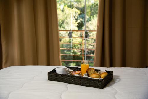 a tray of breakfast foods on a bed with a window at Hotel Serra do Gandarela in Rio Acima