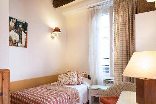 a small room with a bed and a window at Hôtel du Cygne Paris in Paris