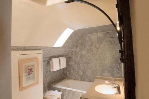 uma casa de banho com um lavatório e uma banheira em Hôtel du Cygne Paris em Paris