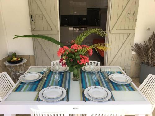 a table with plates and a vase of flowers on it at Villa avec piscine privée in Saint-François