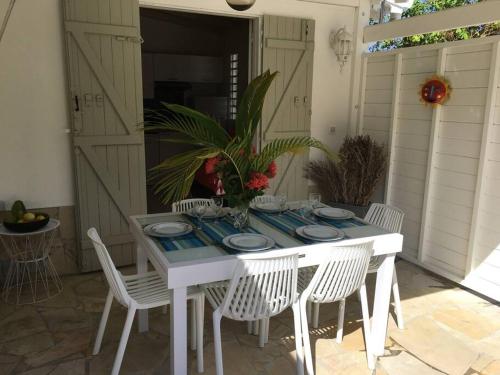 einem weißen Tisch mit Stühlen und Tellern darauf in der Unterkunft Villa avec piscine privée in Saint-François