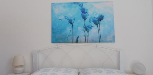 a painting of blue flowers above a bed at Hannas Paradise - Villa Hanna in Skafidia