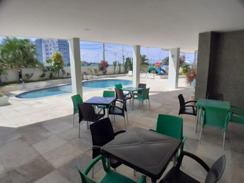 un patio con mesas y sillas y una piscina en Cabo Frio - Praia do Forte - Apto 130 m2 na beira da praia, com ar condicionado, en Cabo Frío