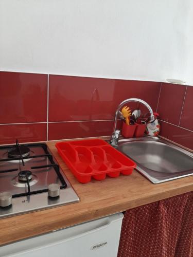 kuchnia ze zlewem, kuchenką i czerwoną ścianą w obiekcie La Melagrana w mieście Castellammare del Golfo