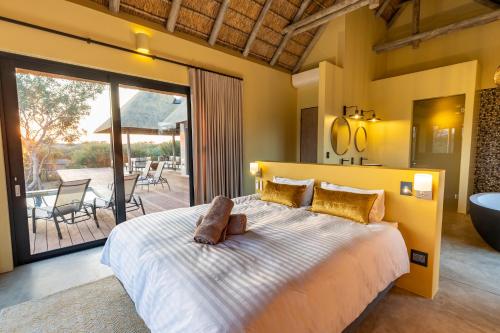 a bedroom with a large bed with a tub and a balcony at Villa Tall Horse - solar powered in Hoedspruit