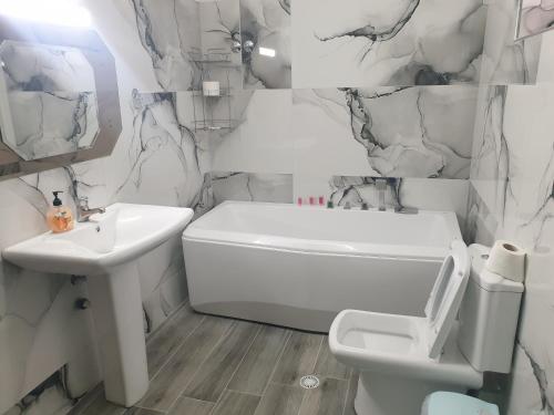 Baño blanco con lavabo y aseo en Jordhani's House, en Korçë