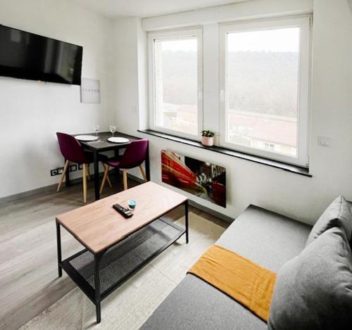 ein Wohnzimmer mit einem Sofa und einem Tisch in der Unterkunft Sympathique petit Studio à la frontière du Luxembourg in Knutange