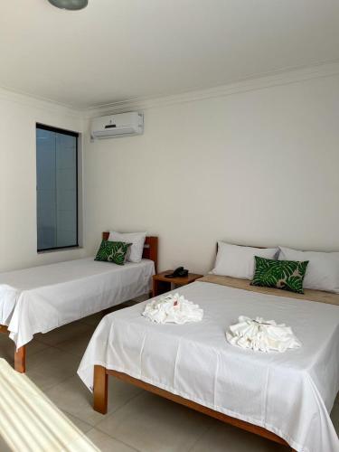 a bedroom with two beds with white sheets at Minas Hotel Unidade Centro in Mariana