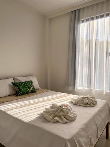 a white bed with two towels on it with a window at Minas Hotel Unidade Centro in Mariana