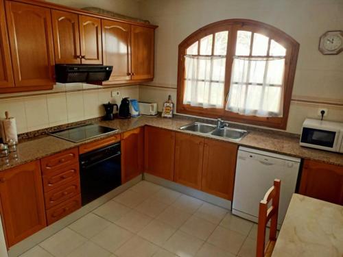 a kitchen with wooden cabinets and a sink and a window at Chalet a 100m de la playa de Cristal, Pino Alto in Hospitalet de l'Infant