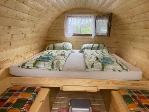a bed in a wooden cabin with a window at Donaucamping Emmersdorf in Emmersdorf an der Donau