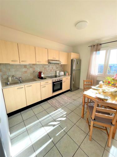 une cuisine avec des placards en bois et une table avec une table dans l'établissement SunnyF2- EuroAiport-Basel-TrainStation-CityCenter, à Saint-Louis
