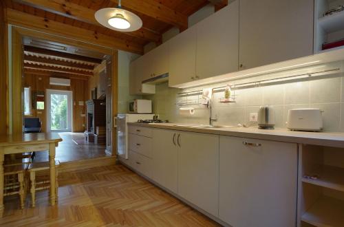 a large kitchen with white cabinets and a wooden floor at Forest Cottage in Neringa