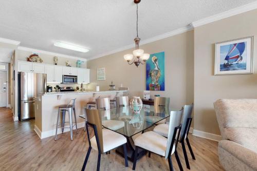 a dining room and kitchen with a glass table and chairs at Regency Isle 411 in Orange Beach