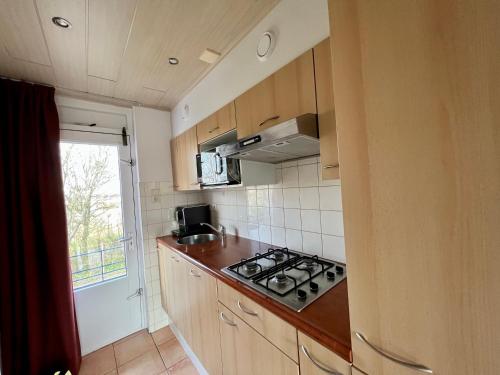 a small kitchen with a stove and a window at Vakantiehuisje Martina 26 in Vlissingen