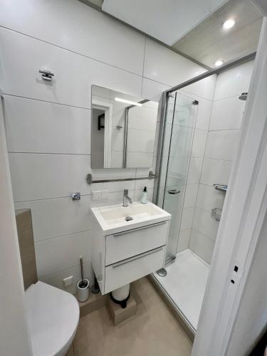 a white bathroom with a sink and a shower at Vakantiehuisje Martina 26 in Vlissingen