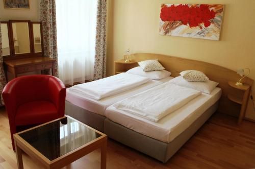a hotel room with two beds and a red chair at Hotel Graf Stadion in Vienna
