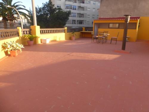 a patio with tables and chairs and a yellow building at Vacaciones tierra y mar Casa en el centro con patio y terraza in El Campello