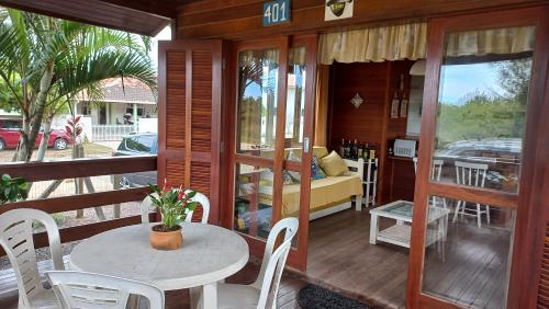 a room with a table and chairs on a porch at La Tatuira, Cabana Amarela in Pinheira