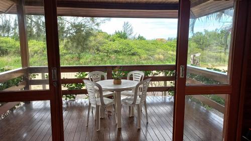 a table and chairs on a balcony with a view at La Tatuira, Cabana Amarela in Pinheira